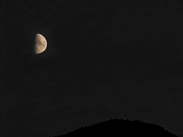The moon rises over the mountains to the east.
